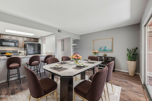 dining room featuring visible vents, light wood-type flooring, and baseboards