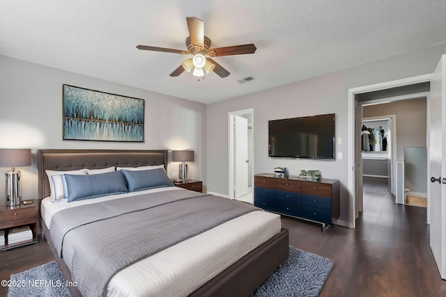 bedroom with dark wood-style floors, visible vents, ceiling fan, and baseboards