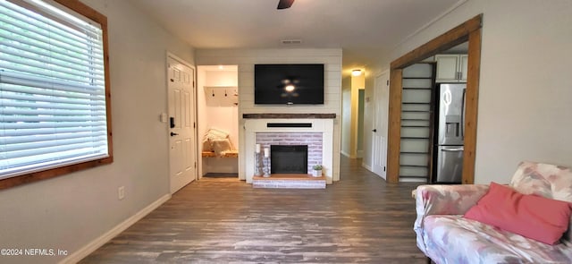 living room featuring a fireplace, ceiling fan, and dark wood-type flooring