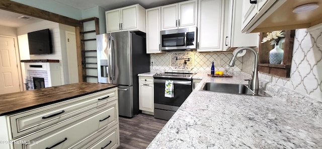 kitchen with wooden counters, sink, decorative backsplash, appliances with stainless steel finishes, and white cabinetry