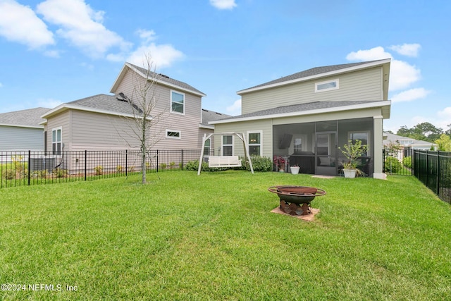 back of house featuring a fire pit, a lawn, and a sunroom