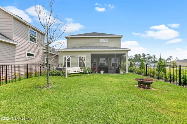 back of house featuring a fire pit, a lawn, and a sunroom