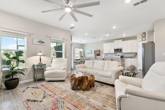 living room with ceiling fan, sink, and a wealth of natural light