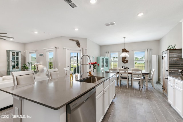 kitchen featuring white cabinetry, dishwasher, sink, hanging light fixtures, and a center island with sink