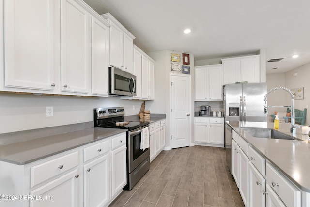 kitchen with white cabinets, light hardwood / wood-style floors, sink, and appliances with stainless steel finishes