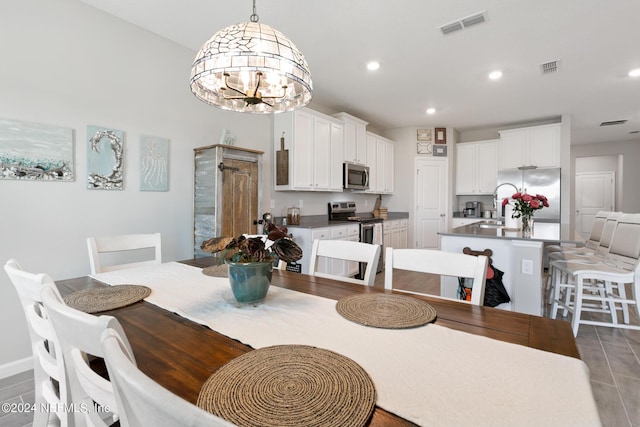 dining area with dark tile patterned floors, sink, and a chandelier