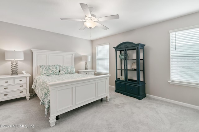 bedroom featuring light colored carpet, multiple windows, and ceiling fan