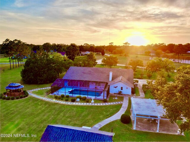 pool at dusk featuring a fire pit, a patio, and a lawn