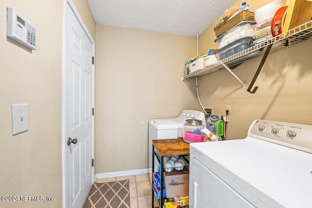 washroom featuring a textured ceiling, washing machine and dryer, and light tile patterned flooring