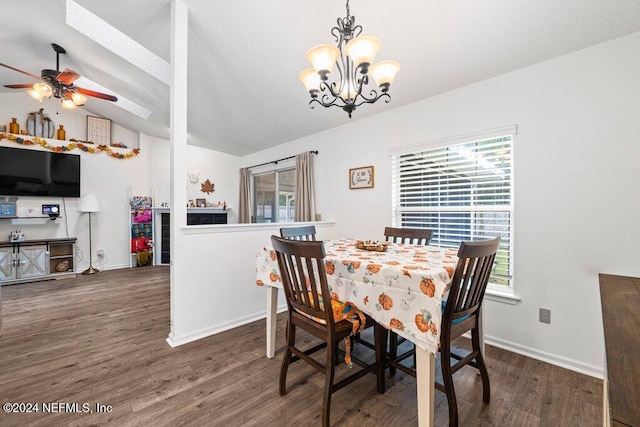 dining space featuring ceiling fan with notable chandelier, dark hardwood / wood-style floors, lofted ceiling with skylight, and a wealth of natural light