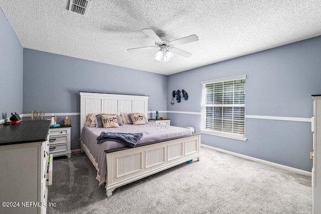 bedroom featuring a textured ceiling, dark carpet, and ceiling fan