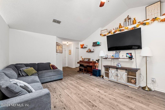 living room with a textured ceiling, ceiling fan, vaulted ceiling, and hardwood / wood-style flooring