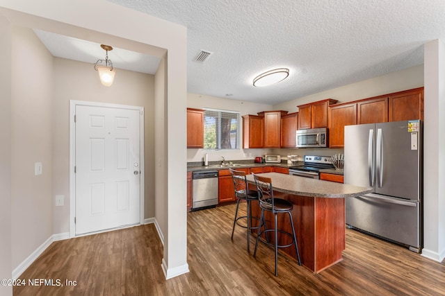 kitchen with visible vents, dark countertops, appliances with stainless steel finishes, a kitchen bar, and a sink