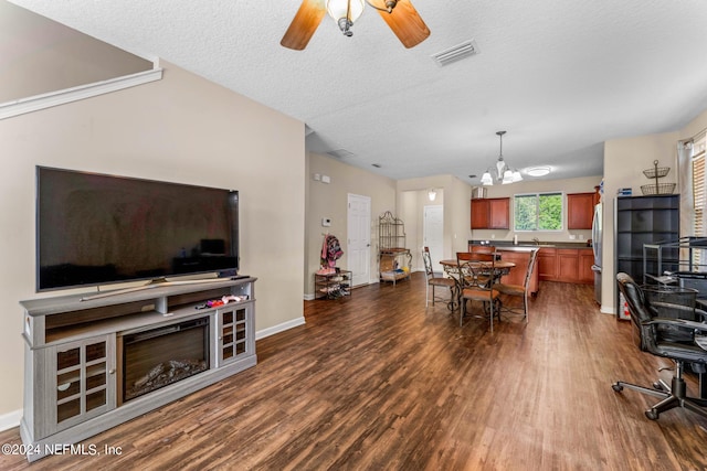 dining space with dark wood finished floors, visible vents, a textured ceiling, baseboards, and ceiling fan with notable chandelier