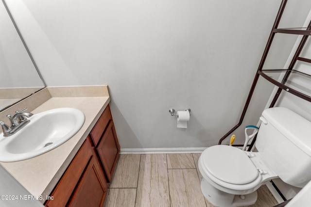 bathroom featuring wood finished floors, vanity, toilet, and baseboards