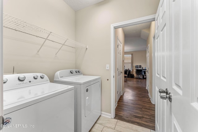 washroom featuring laundry area, baseboards, a textured ceiling, and independent washer and dryer