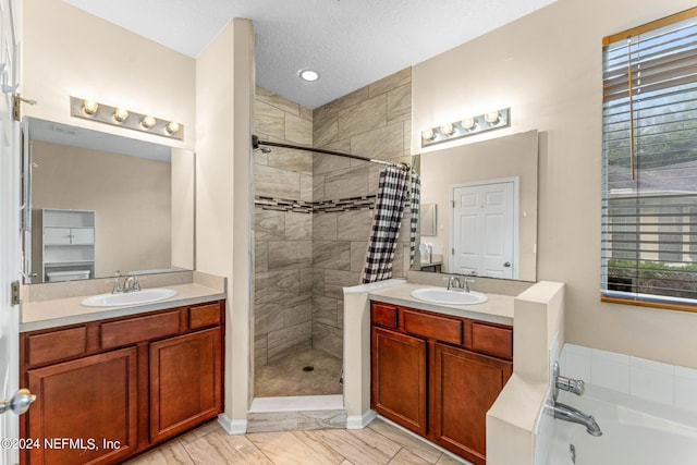 full bath with a stall shower, two vanities, a sink, and a bath