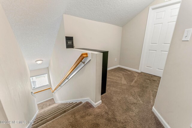 staircase with a textured ceiling, carpet, and vaulted ceiling