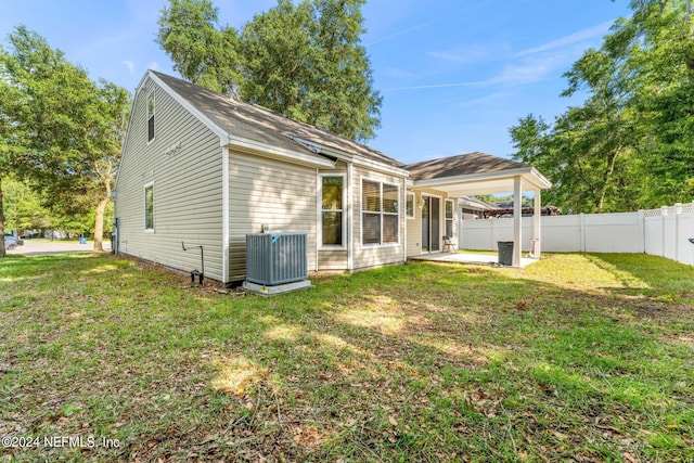 rear view of property with a patio area, a lawn, fence, and central AC