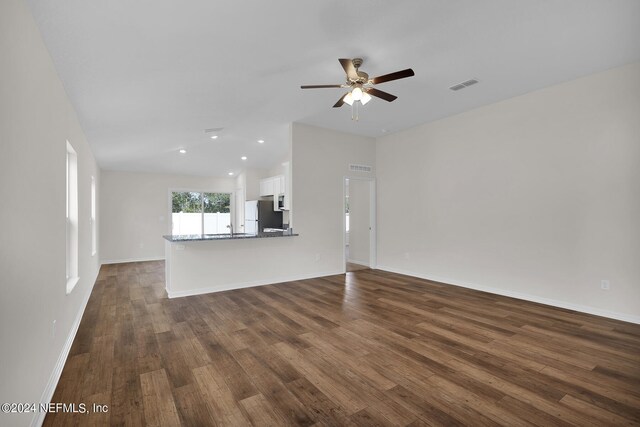 unfurnished living room featuring ceiling fan and dark hardwood / wood-style flooring