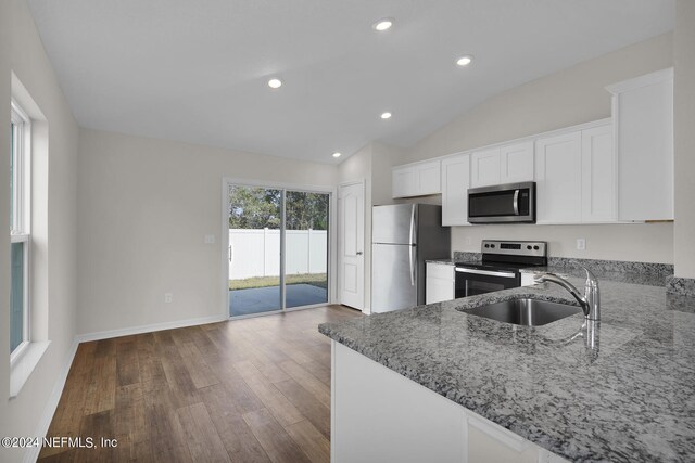 kitchen featuring kitchen peninsula, dark hardwood / wood-style flooring, stainless steel appliances, vaulted ceiling, and sink