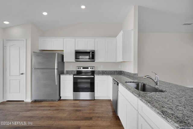 kitchen with appliances with stainless steel finishes, dark wood-type flooring, sink, white cabinetry, and lofted ceiling