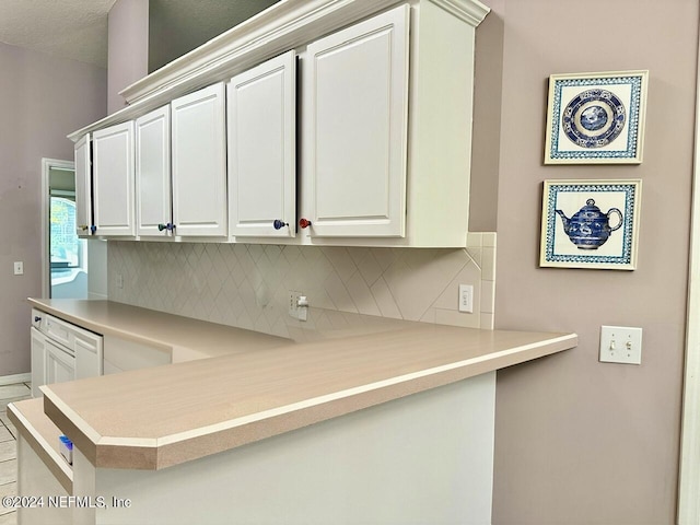 kitchen featuring kitchen peninsula, decorative backsplash, and white cabinets