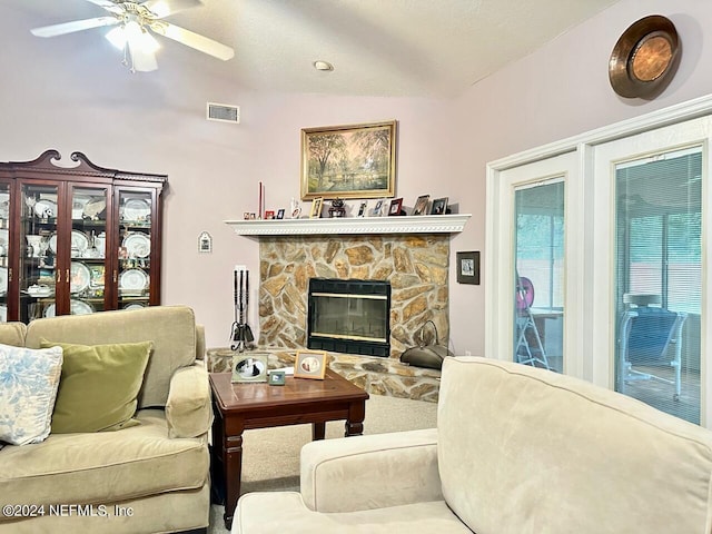 living room featuring ceiling fan, a fireplace, and vaulted ceiling