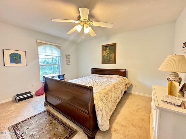 bedroom featuring a textured ceiling, ceiling fan, and light carpet