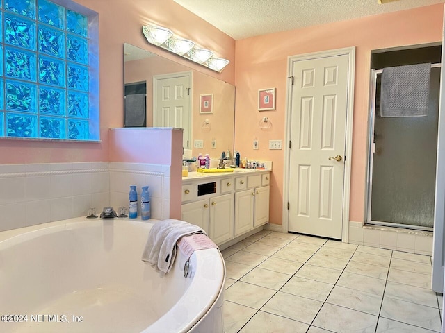 bathroom with tile patterned floors, plus walk in shower, vanity, and a textured ceiling