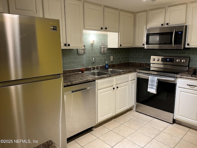 kitchen with appliances with stainless steel finishes, sink, light tile patterned floors, and white cabinets