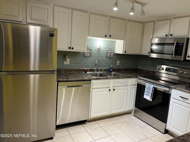 kitchen featuring light tile patterned flooring, appliances with stainless steel finishes, sink, white cabinets, and backsplash