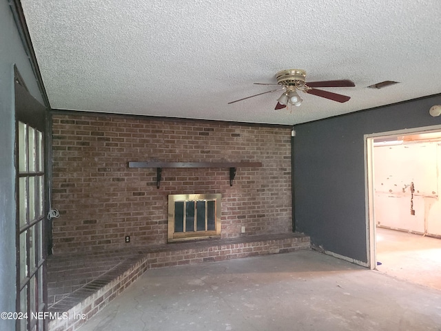 unfurnished living room featuring ceiling fan, a brick fireplace, a textured ceiling, and concrete flooring