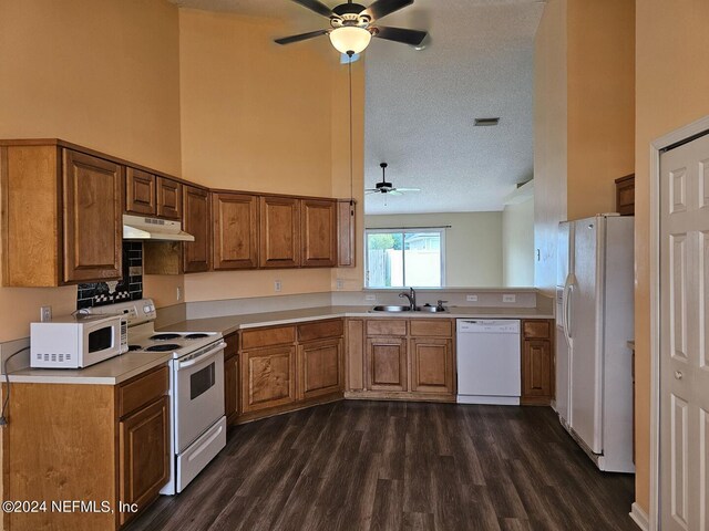 kitchen with a textured ceiling, dark wood-type flooring, white appliances, sink, and ceiling fan