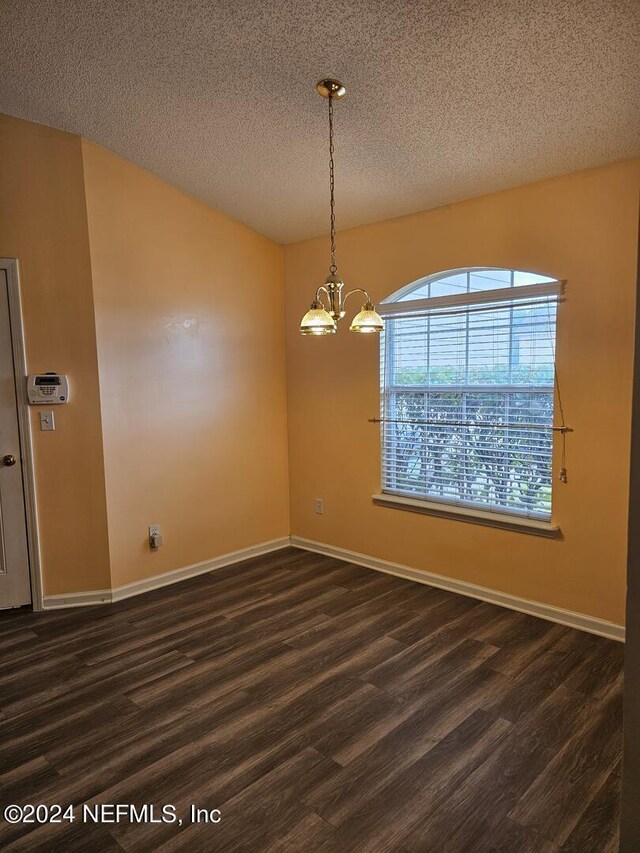 unfurnished room with a chandelier, a textured ceiling, and dark hardwood / wood-style floors