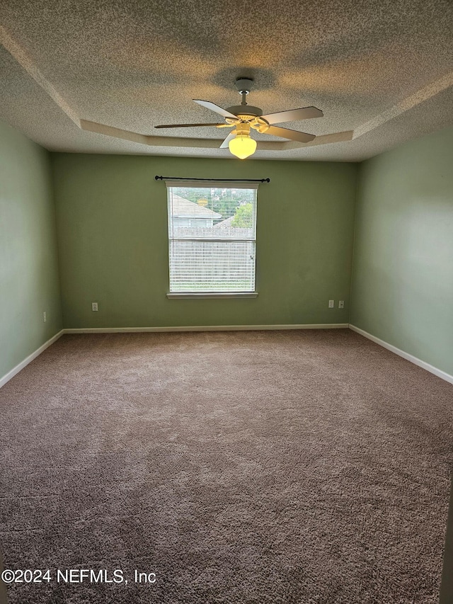 carpeted spare room with ceiling fan, a tray ceiling, and a textured ceiling