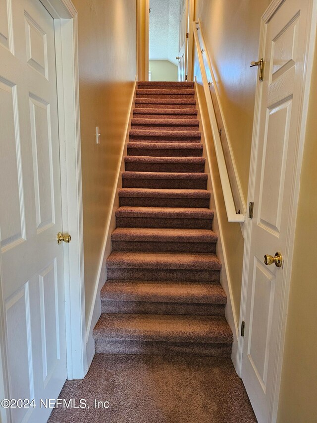 staircase featuring carpet and a textured ceiling