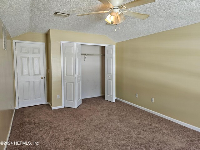 unfurnished bedroom featuring vaulted ceiling, dark carpet, ceiling fan, and a textured ceiling