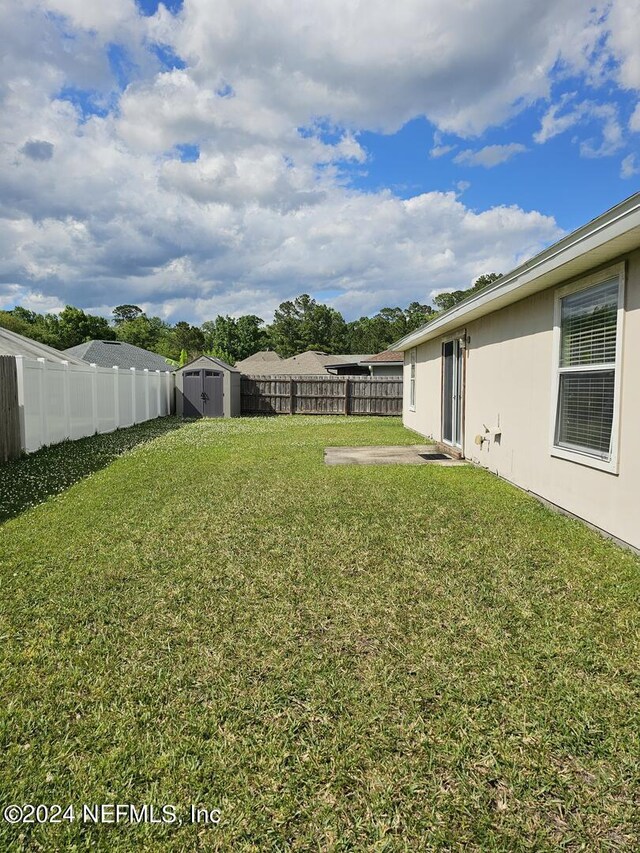 view of yard featuring a fenced backyard, a storage unit, and an outdoor structure