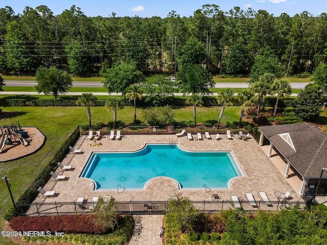 community pool featuring a yard, fence, and a patio