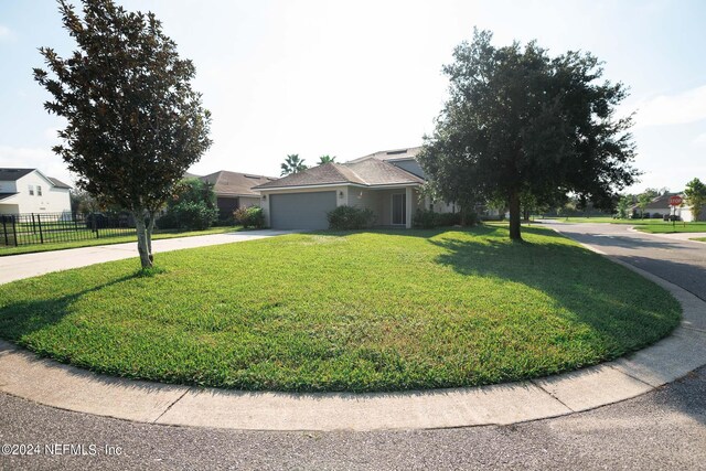 view of front of home with a garage, concrete driveway, a front yard, and fence