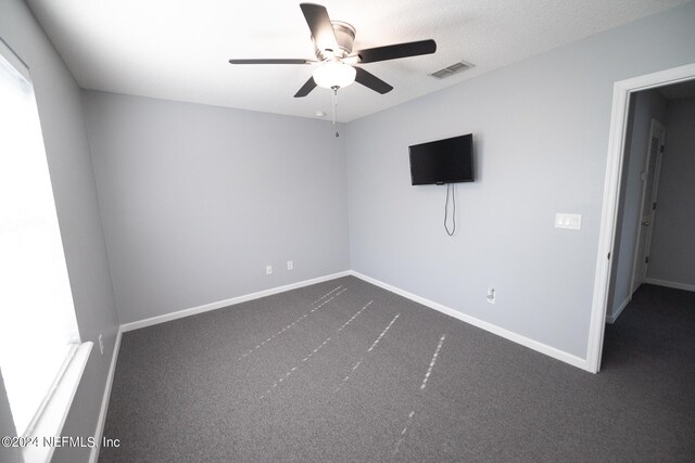 empty room with visible vents, dark carpet, and baseboards