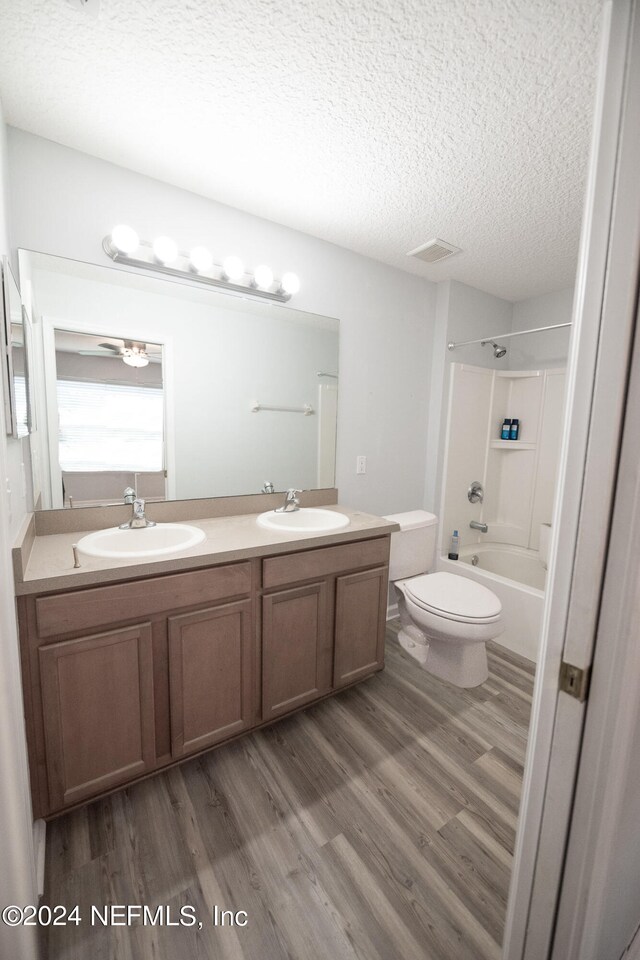 full bathroom featuring a sink, a textured ceiling, toilet, and wood finished floors