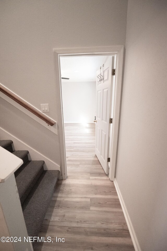 hall featuring stairway, wood finished floors, and baseboards