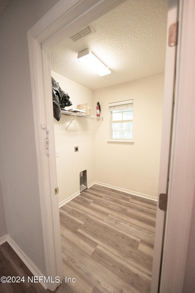 laundry room with laundry area, baseboards, visible vents, wood finished floors, and a textured ceiling