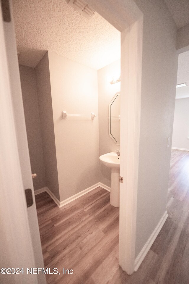 bathroom featuring a textured ceiling, baseboards, and wood finished floors