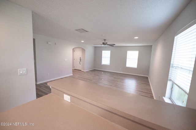 spare room featuring baseboards, a textured ceiling, arched walkways, and wood finished floors