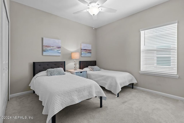 bedroom with a closet, light colored carpet, and ceiling fan