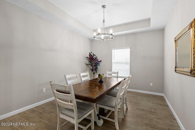 dining area featuring a raised ceiling and an inviting chandelier