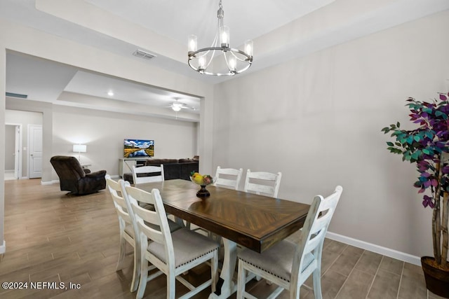 dining room featuring a raised ceiling and ceiling fan with notable chandelier